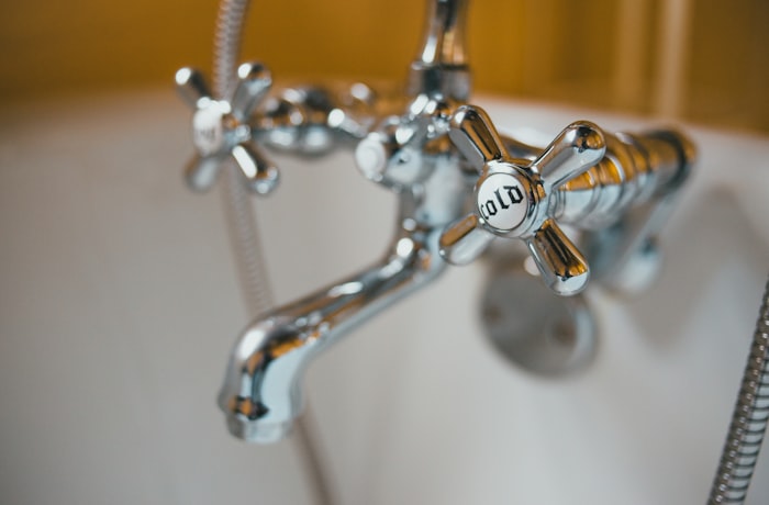 Silver faucet with water droplets indicating a leak