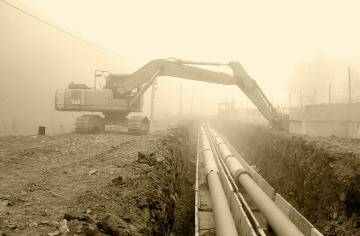 Excavator working on large sewer pipe installation